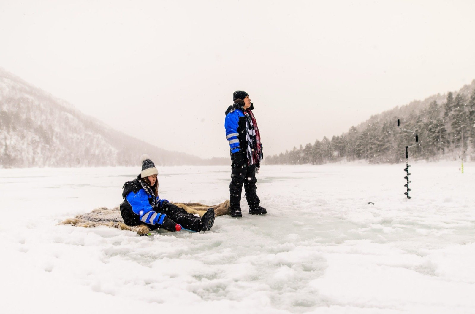 Two guests ice fishing on a frozen lake